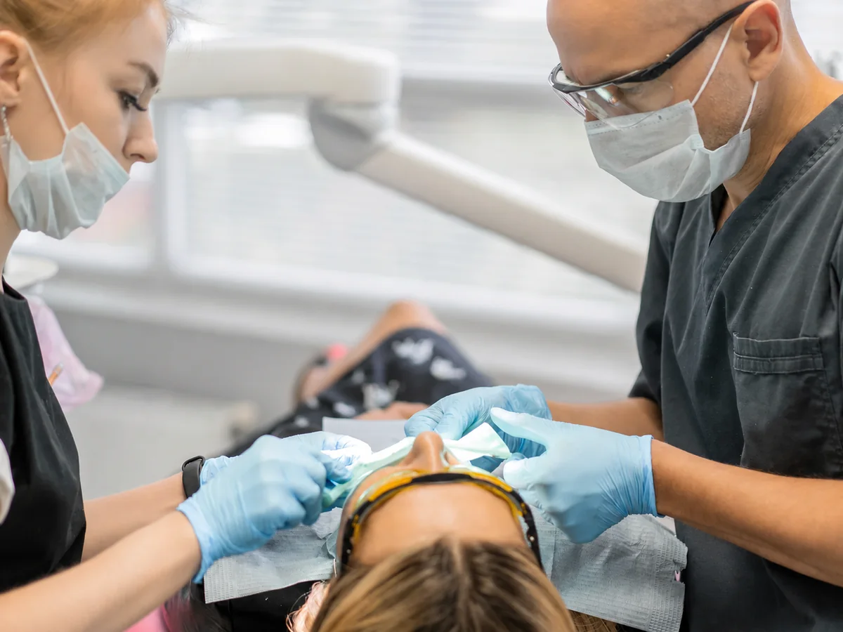 Zwei Behandelnde arbeiten gemeinsam an einer Patientin